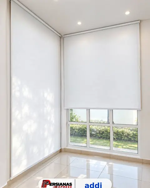 Persiana enrollable blanca en esquina de sala con ventanas